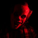 Silhouette masquée éclairée en rouge évoquant un film d'horreur